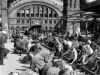 A large group of people, adults and children, sit on the edge of the train tracks near the Brandenberg Gate, Berlin, Germany, August 1945. (Photo by Margaret Bourke White/ © Time & Life Pictures/Getty Images)